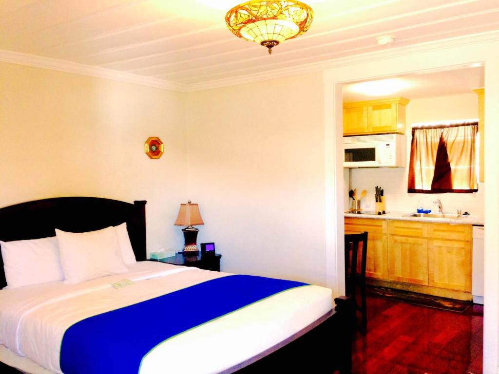 a bedroom with a blue and white bed and a kitchen at Americas Best Value Inn Royal Carriage in Jamestown