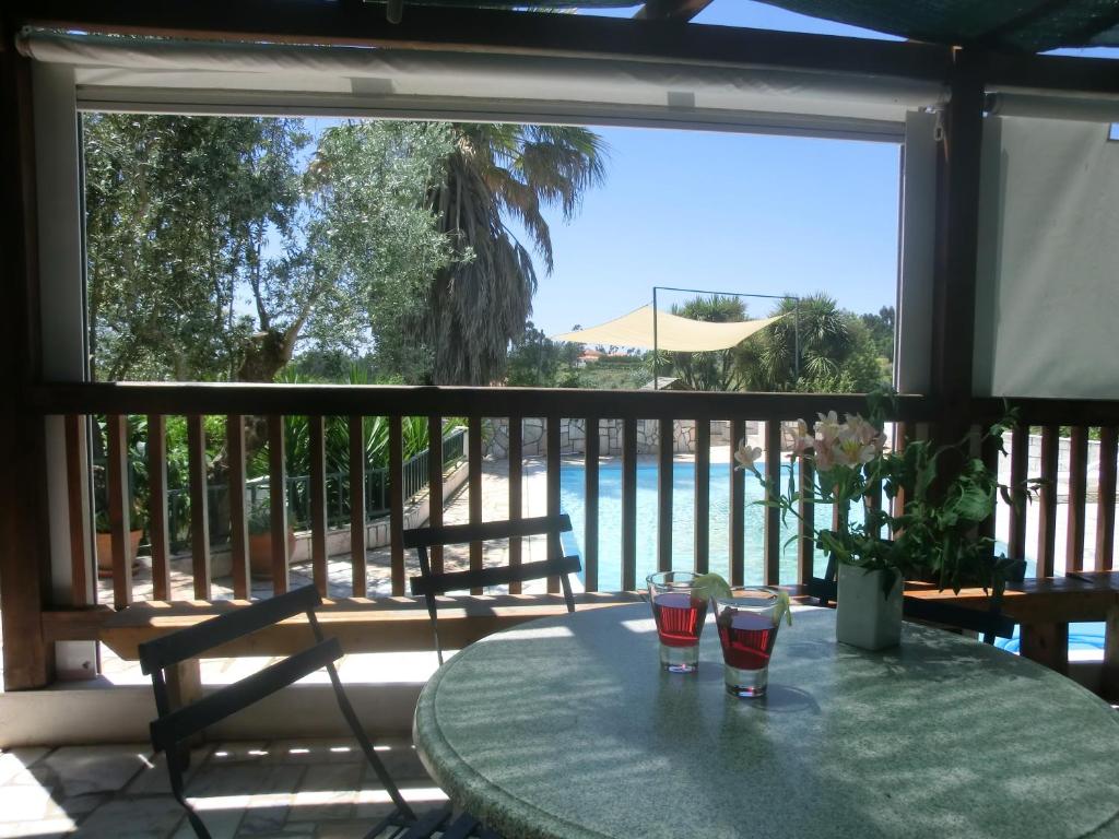 a table with two glasses on a balcony with a pool at Redondo Lodges in Junceira