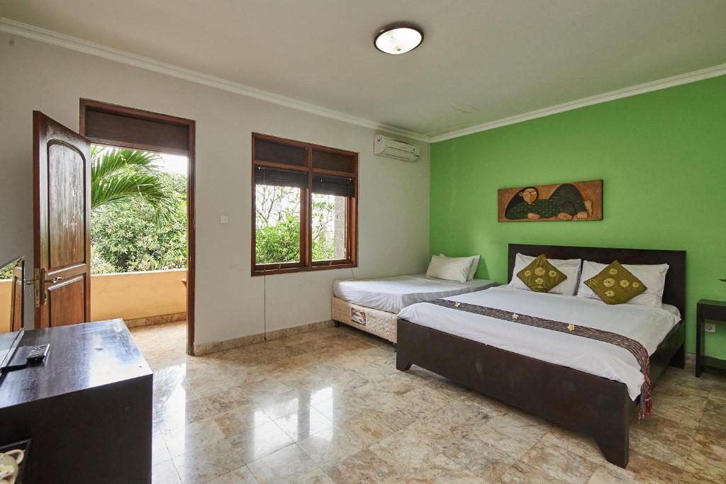 a bedroom with two beds in a room with green walls at Ellies Hotel in Nusa Dua