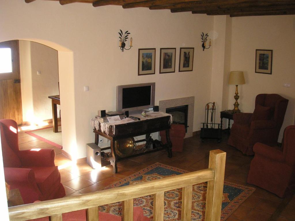 a living room with a television and a fireplace at Casa da Silveirinha in Marvão