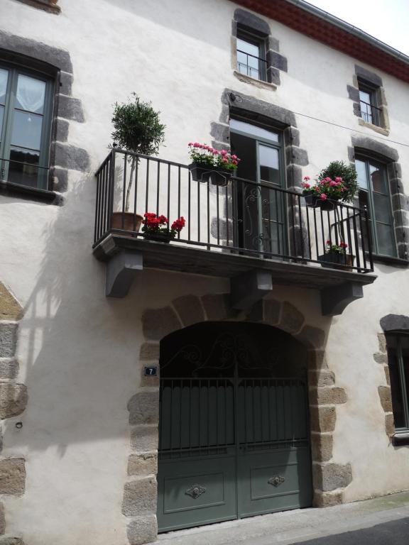 a building with a balcony with flowers on it at Les quatre provinces d'Irlande in Saint-Amant-Tallende