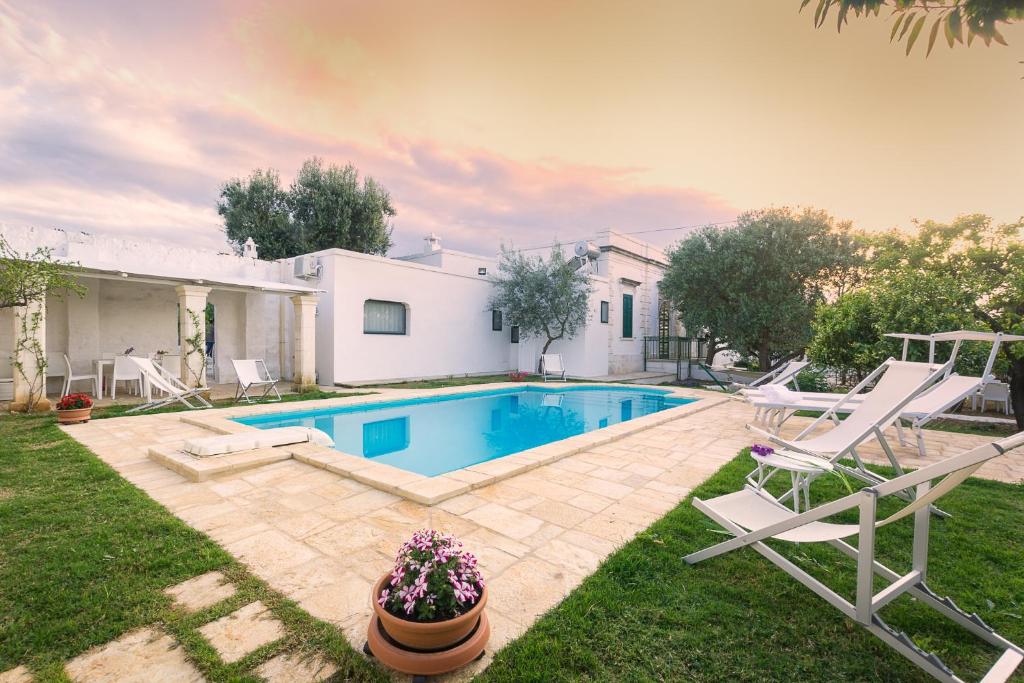 a house with a swimming pool and two lawn chairs at Casale Cappuccio Apartments in Ostuni
