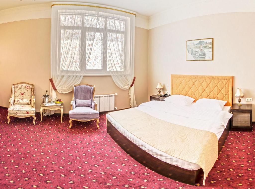 a hotel room with a large bed and two chairs at Hyde Park Hotel in Tver