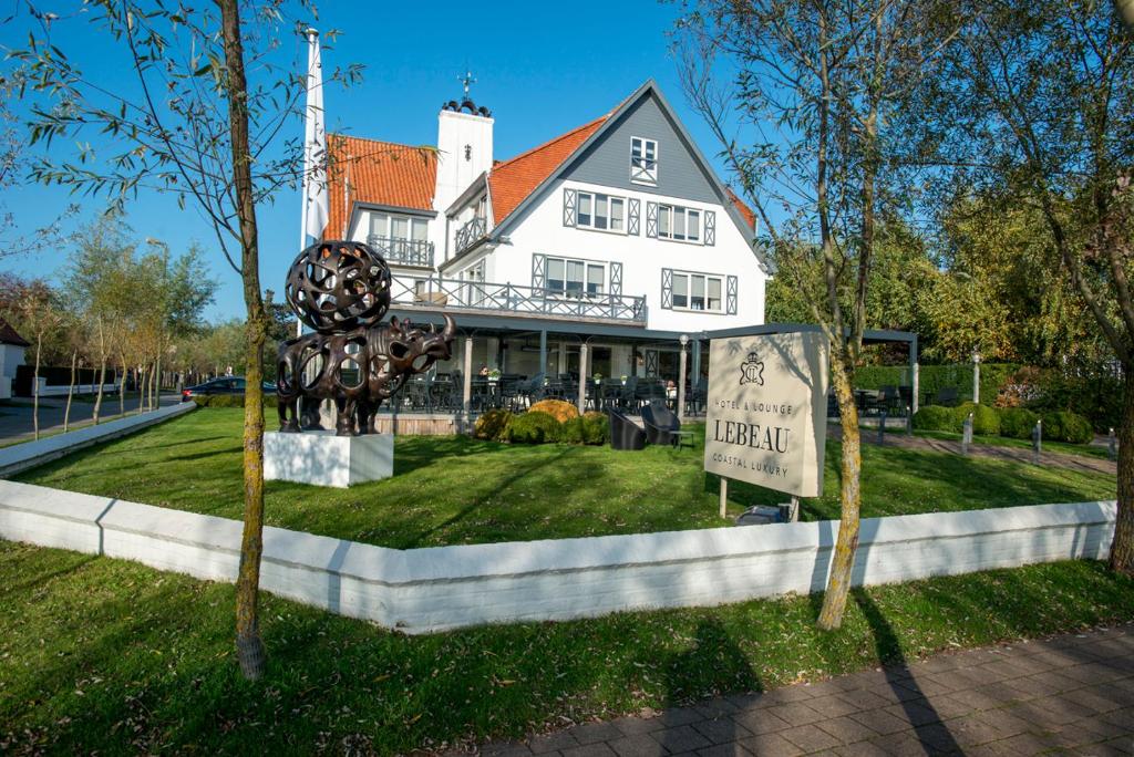 Une grande maison blanche avec une statue en face de celle-ci dans l'établissement Lebeau 19 Hotel, à Knokke-Heist