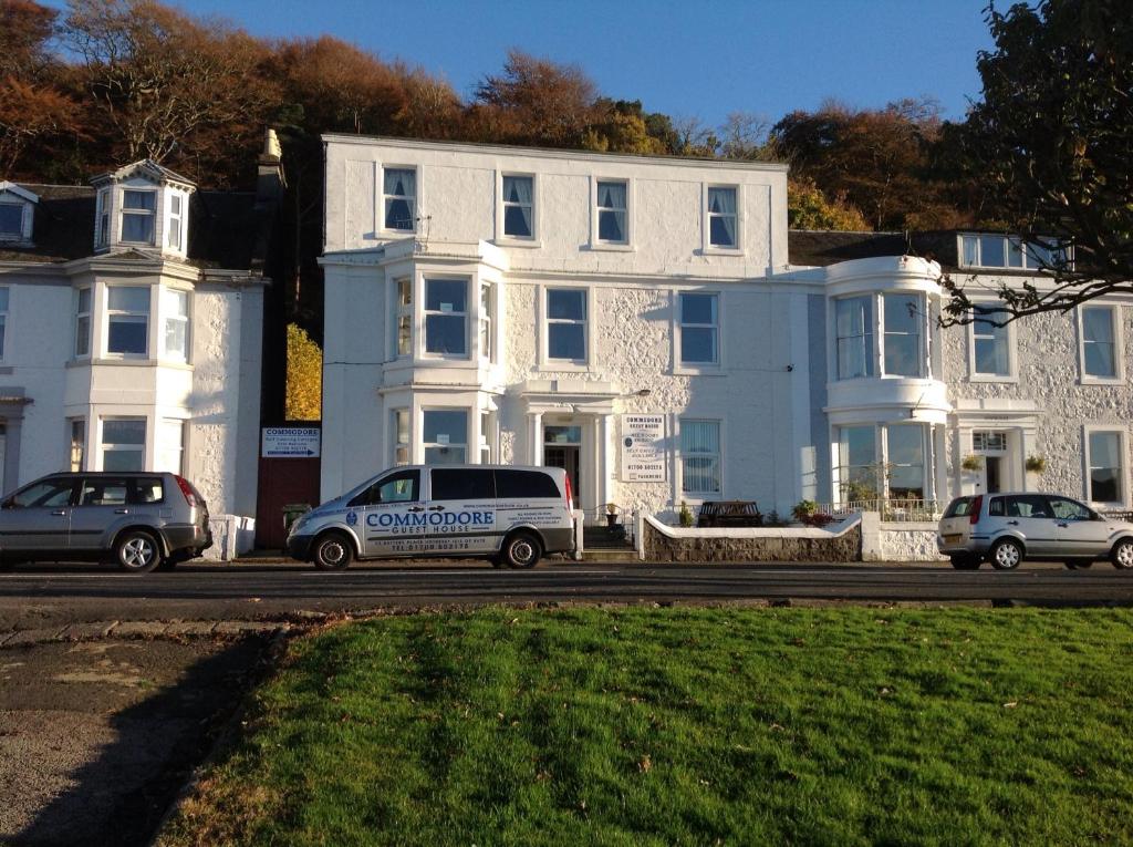 Una casa blanca con una furgoneta de policía estacionada frente a ella. en Commodore Guesthouse, Self-Catering Suites, en Rothesay