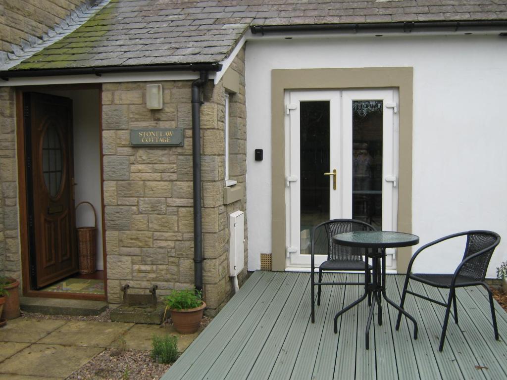 a patio with two chairs and a table on a deck at StoneLaw Cottage in Longframlington