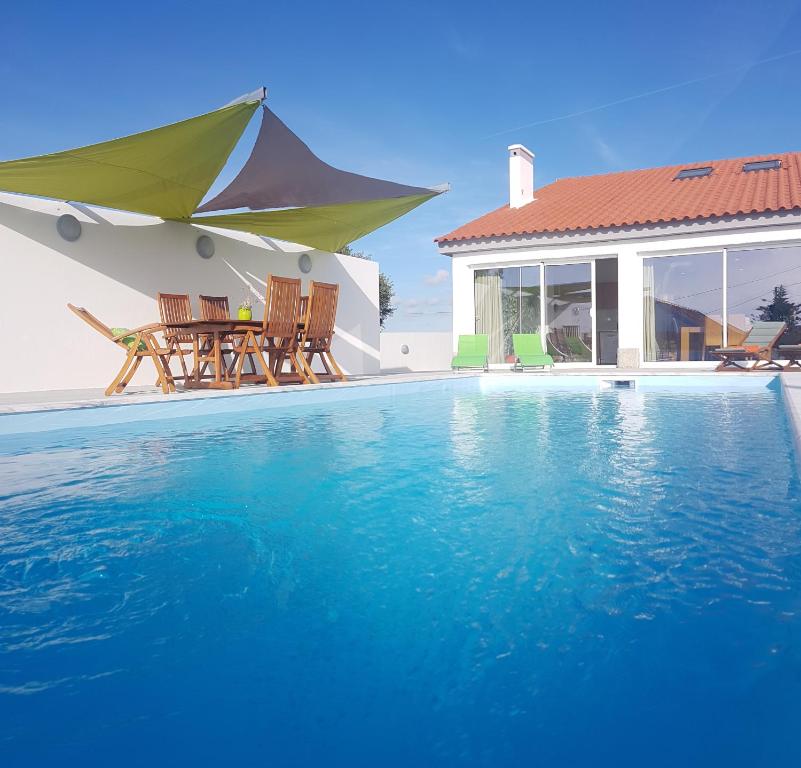 a swimming pool with two chairs and a house at Nira House Luxury & Simplicity in Ericeira
