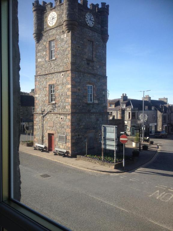a building with a clock tower on a street at Acorn Apartment in Dufftown