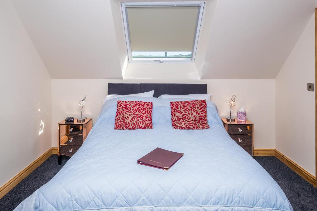 a bed with two red pillows and a purse on it at Lazy Days in Whitby
