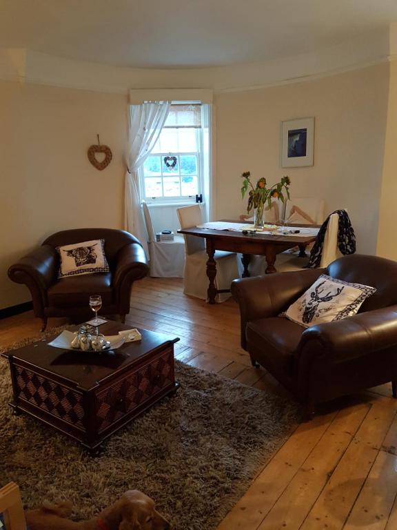 a living room with leather furniture and a table at Argyll Mansions Penthouse in Oban