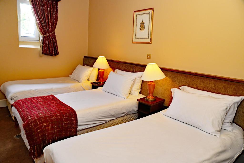 two beds in a hotel room with two lamps at Gabriel House Guesthouse in Cork
