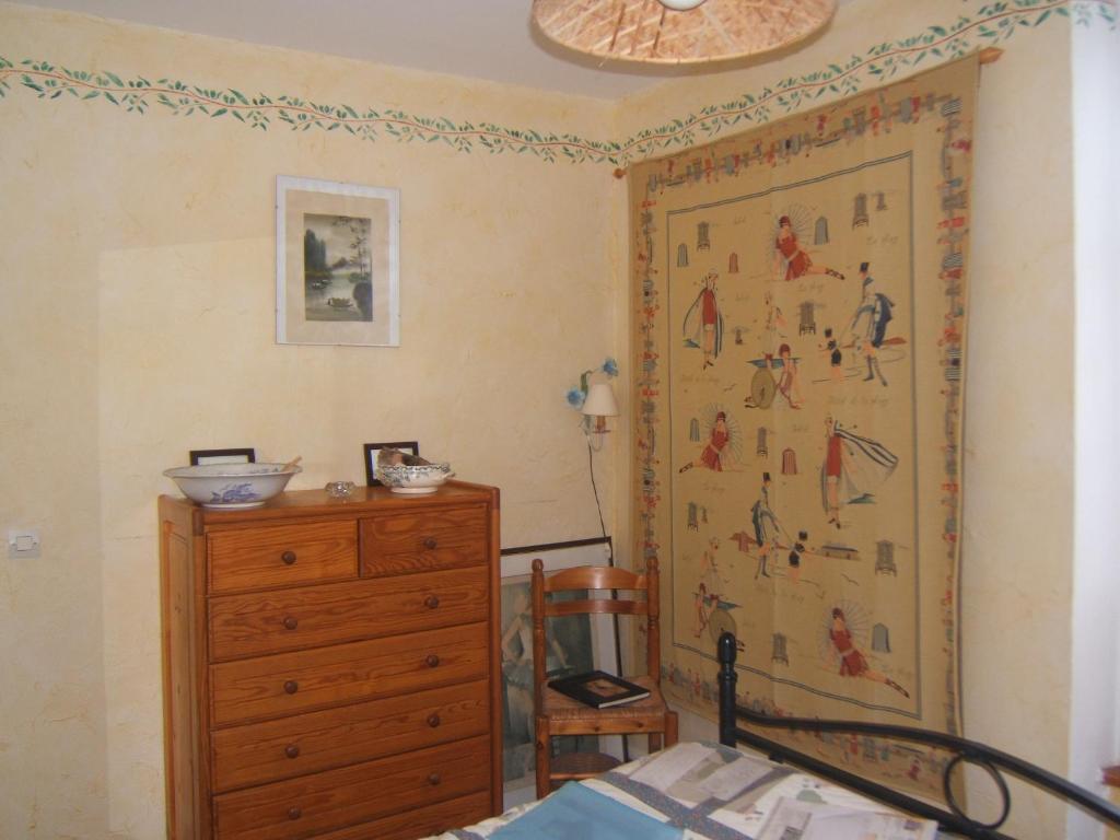 um quarto com uma cómoda e uma pintura na parede em Relais du Cap romain em Saint-Aubin-sur-Mer