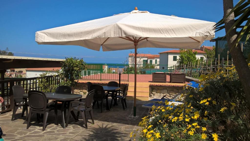 eine Terrasse mit Tischen und Stühlen unter einem Sonnenschirm in der Unterkunft Bed & Breakfast - Anselmi M&M in Marciana
