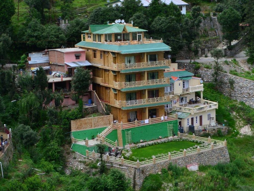 a large house with a green roof on a hill at The Golden Peak, Hotel in Mukteswar