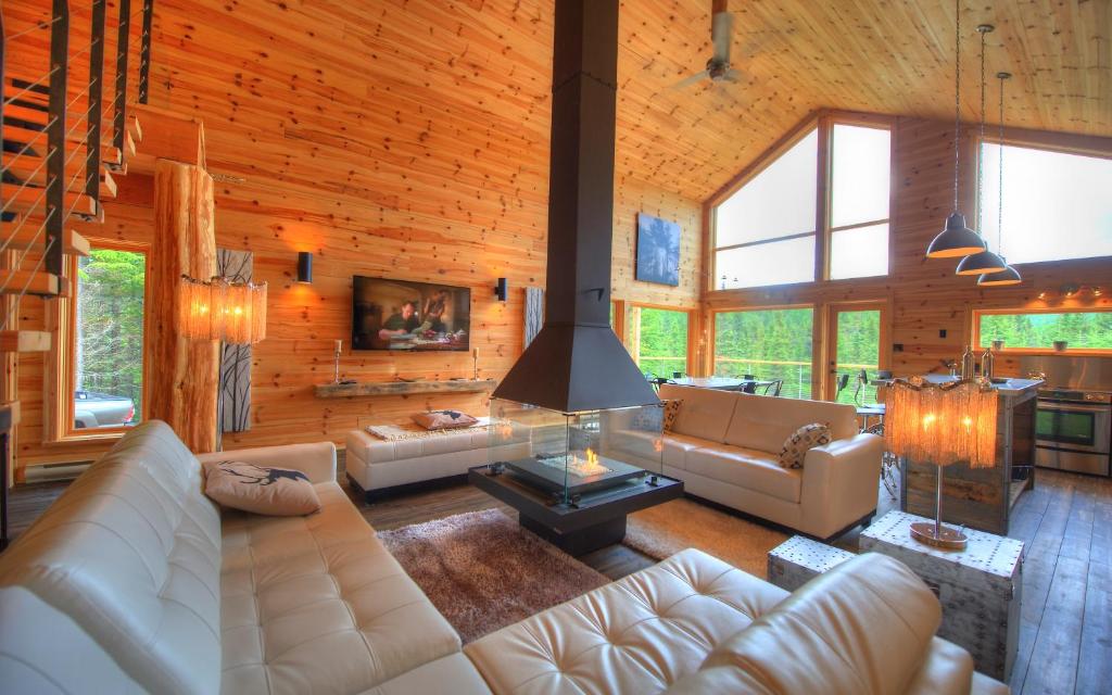 a living room with white furniture in a log cabin at Le Val d'Isère - Les Chalets Spa Canada in La Malbaie