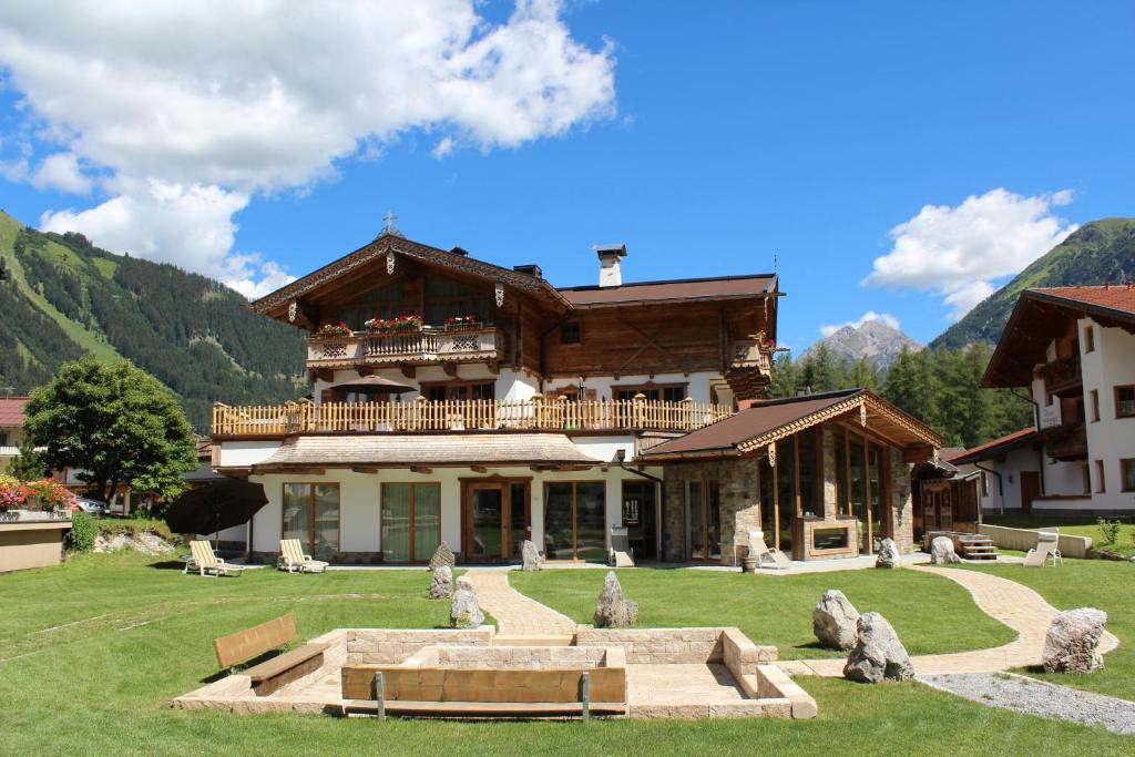 a large wooden house with a garden in front of it at Chaletresort Lech in Holzgau