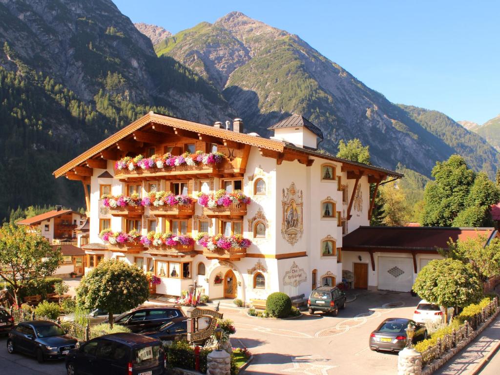 a building with flowers on the balconies in front of mountains at Oberlechtaler Hof Boutique Hotel in Holzgau