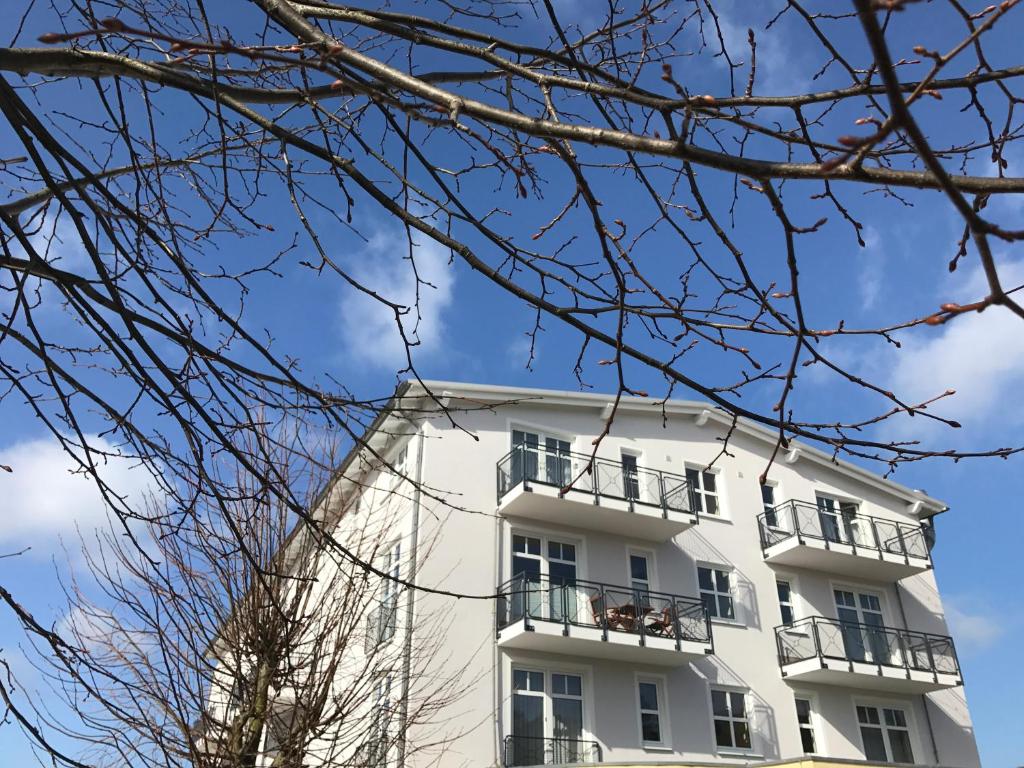 un edificio blanco con balcones y árboles en Ferienwohnung Nummer 22 Sellin, en Ostseebad Sellin