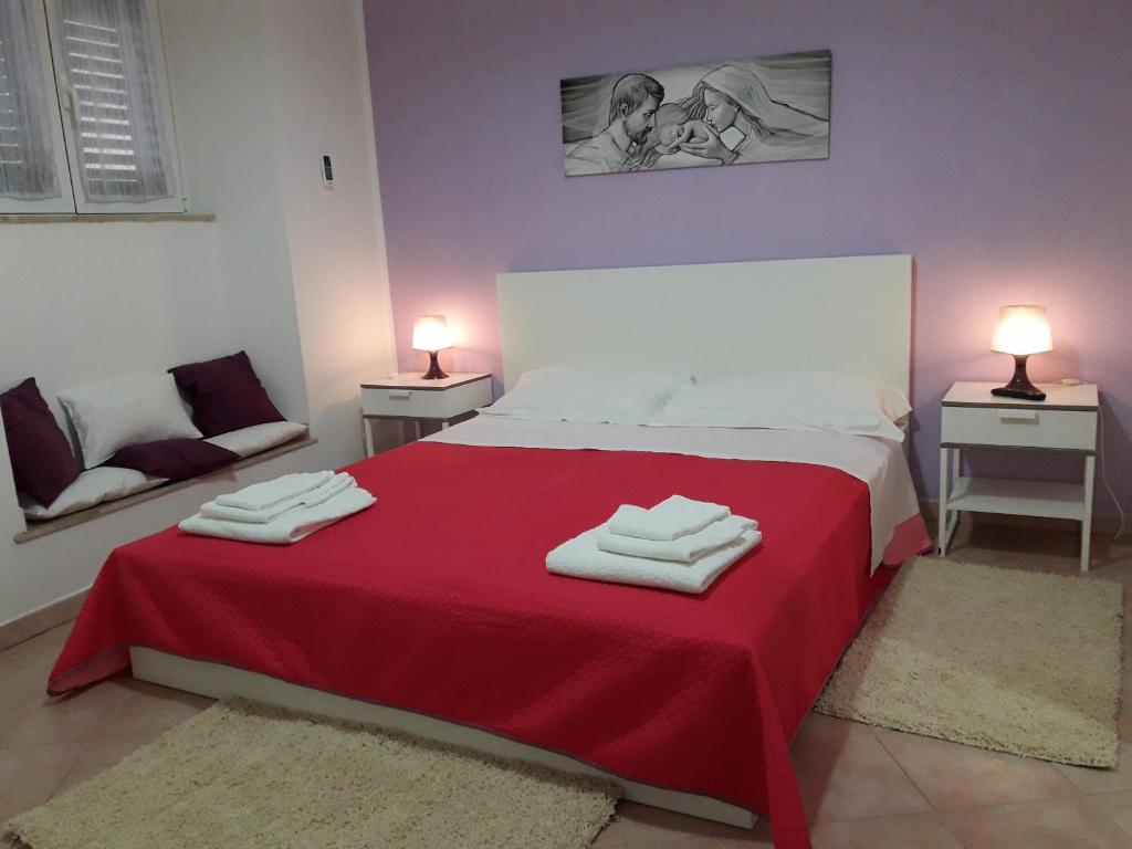 a bedroom with a red bed with towels on it at Casa del Clown in Trapani
