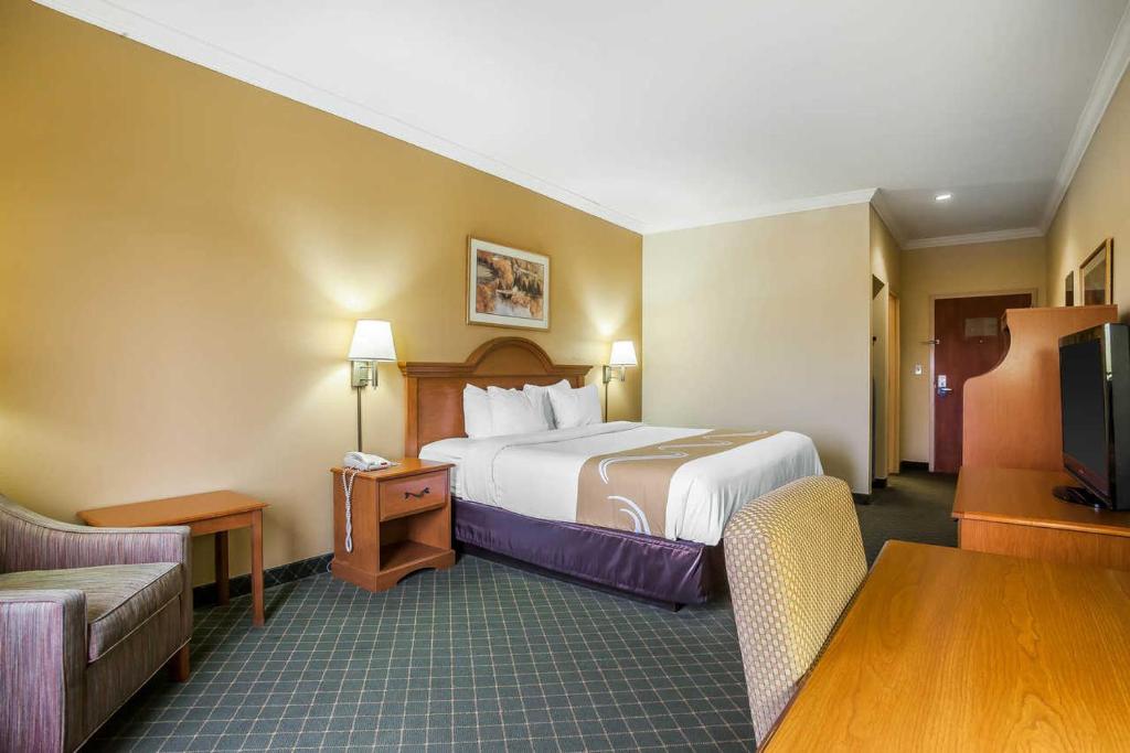 a hotel room with a large bed and a table at Rodeway Inn Tahlequah in Tahlequah