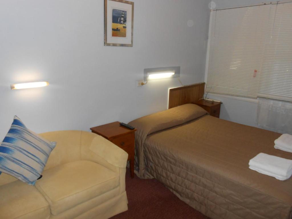 a hotel room with a bed and a chair at Mount View Motel in Bulahdelah