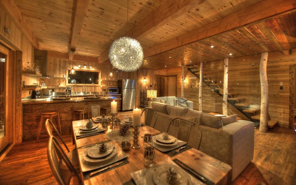 a living room with a table and a couch at Les Bouleaux - Les Chalets Spa Canada in La Malbaie