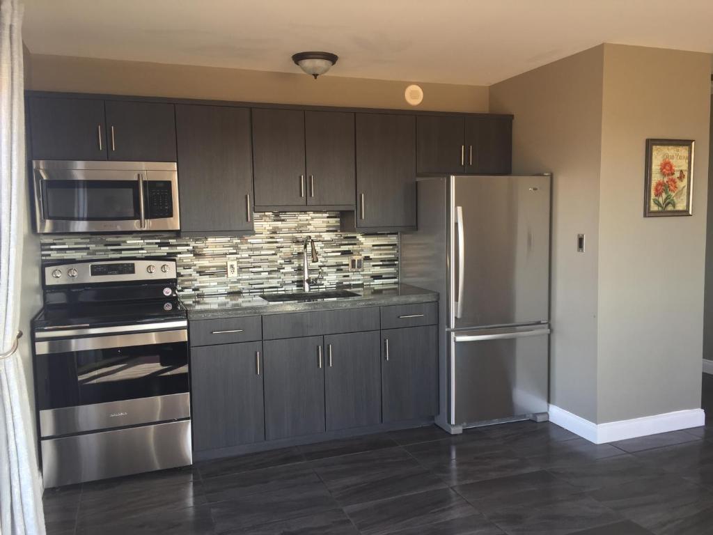 a kitchen with gray cabinets and a stainless steel refrigerator at PEI Cottage Rental in Borden-Carleton
