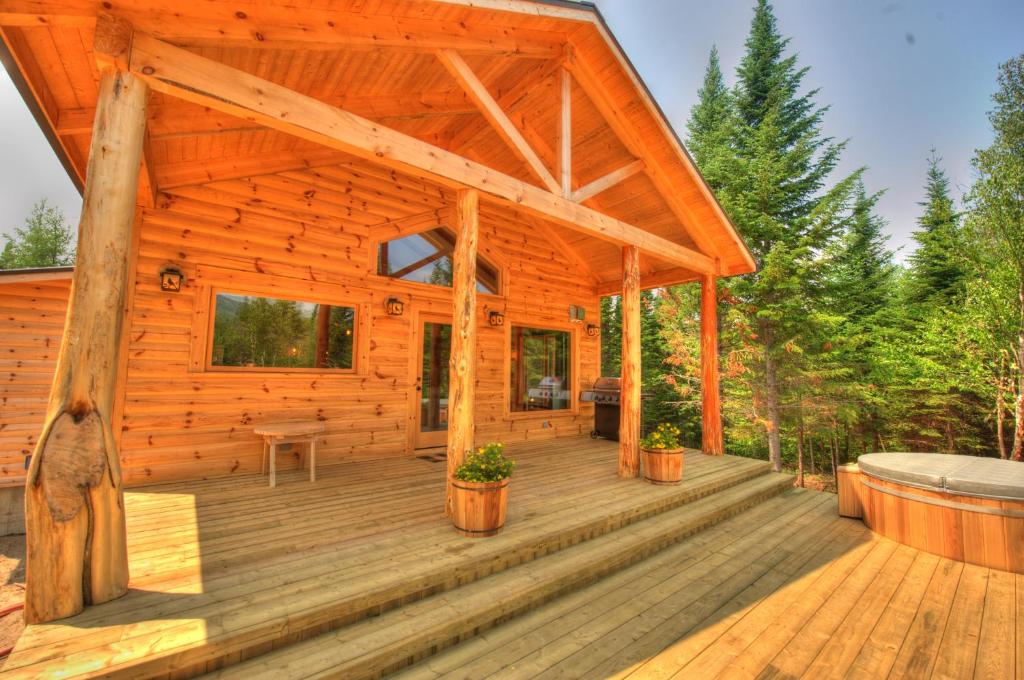 a log cabin with a large wooden deck at Le St Bernard - Les Chalets Spa Canada in La Malbaie