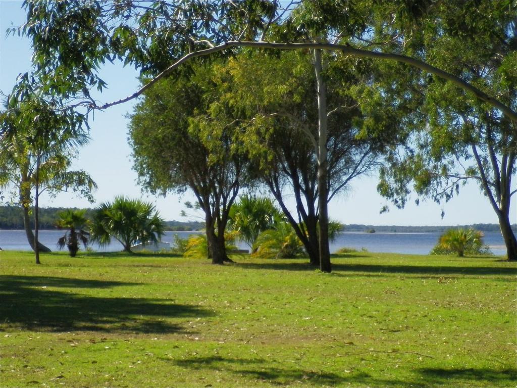 a park with trees and water in the background at Tin Can Bay's Sleepy Lagoon Motel in Tin Can Bay