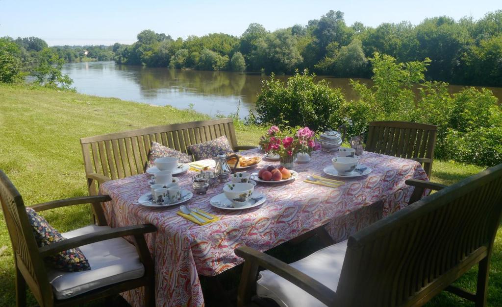 un tavolo con cibo e fiori accanto a un fiume di Le Manoir de la Riviere a Saint-Seurin-de-Prats