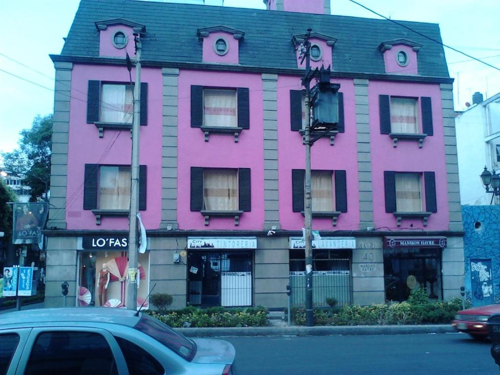 un bâtiment rose avec une voiture garée devant lui dans l'établissement Mansion Havre, à Mexico