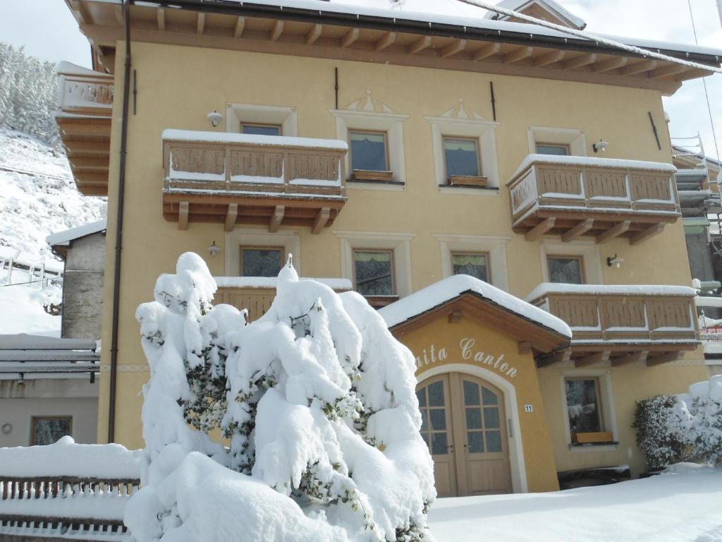a building with snow covered trees in front of it at Baita Canton in Valfurva