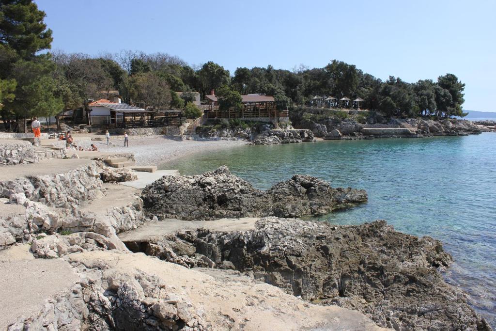 a beach with rocks and people on the water at Apartman Luburić in Pinezici