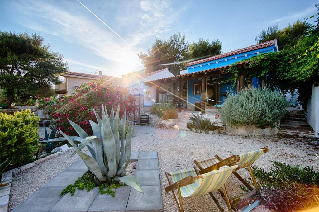 een patio met twee stoelen en een plant en een huis bij The Sea House Apartments in Vis