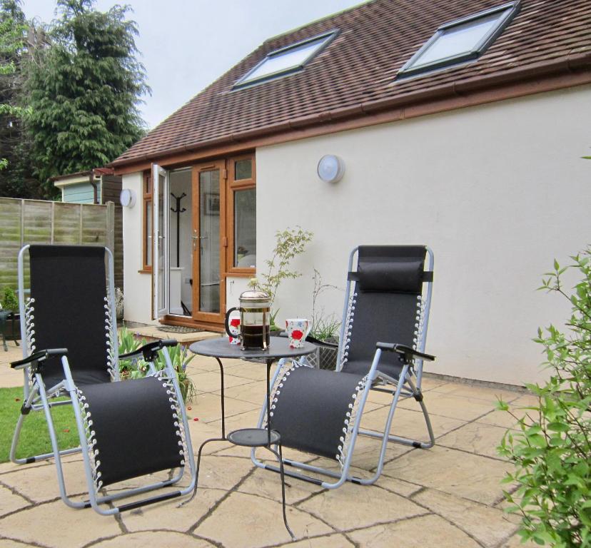 eine Terrasse mit Stühlen und einem Tisch vor einem Haus in der Unterkunft Temeside Garden House in Ludlow