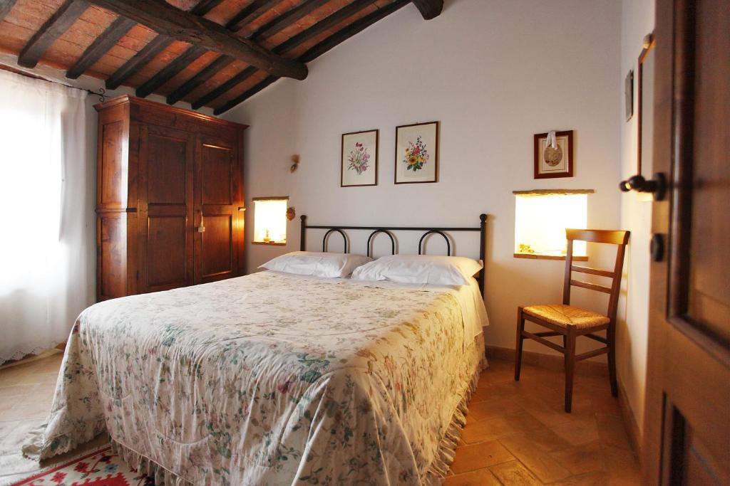 1 dormitorio con 1 cama grande y 1 silla en Casale Giacomini, en Manciano
