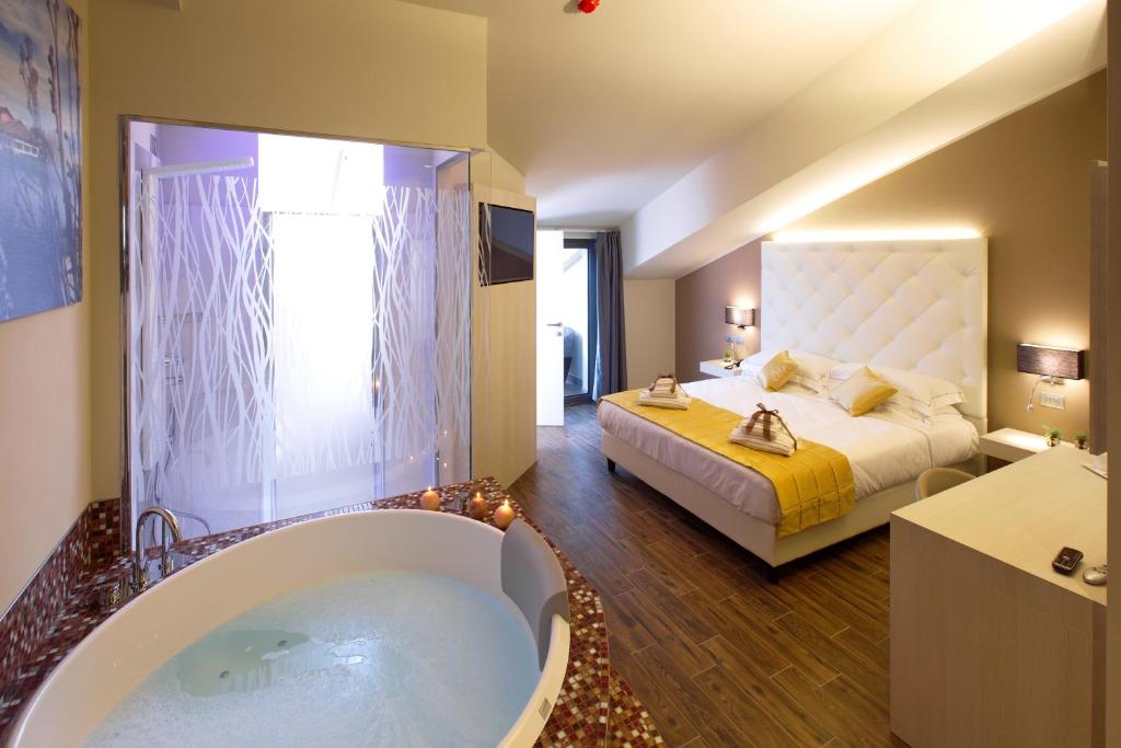 a bedroom with a large tub and a bed at Hotel Terre Dei Salici in Caramagna Piemonte