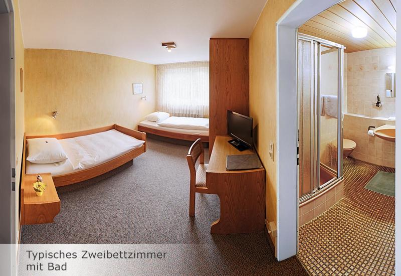 a bedroom with a bed and a desk with a computer at Hotel Keinath Stuttgart in Stuttgart