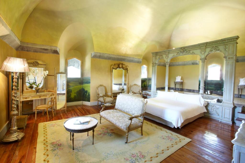 a large bedroom with a large bed and a chair at Hotel Castillo de Arteaga in Gautegiz Arteaga