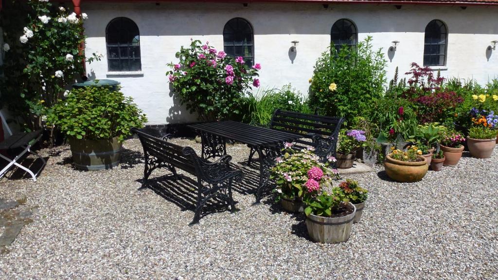 um banco preto sentado ao lado de um monte de vasos de plantas em Gård em Borre