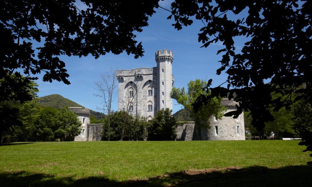 un antiguo castillo con una torre en un campo de hierba en Hotel Castillo de Arteaga, en Gautegiz Arteaga