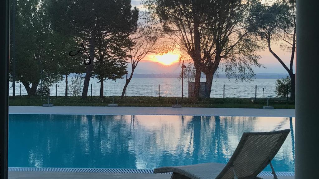 a chair sitting next to a swimming pool with the sunset at Residence Alexandra Stay in Sirmione