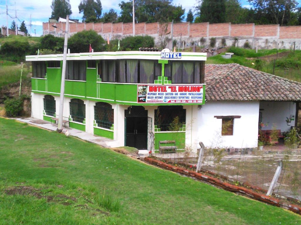 a green and white building on top of a field at Casa Huespedes El Molino in Tababela
