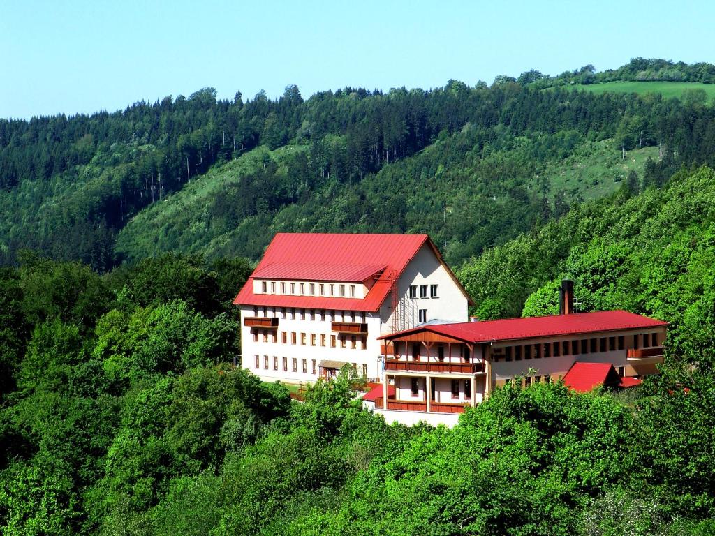 un gran edificio con techo rojo en una colina en Hotel Vrsatec, en Vršatské Podhradie