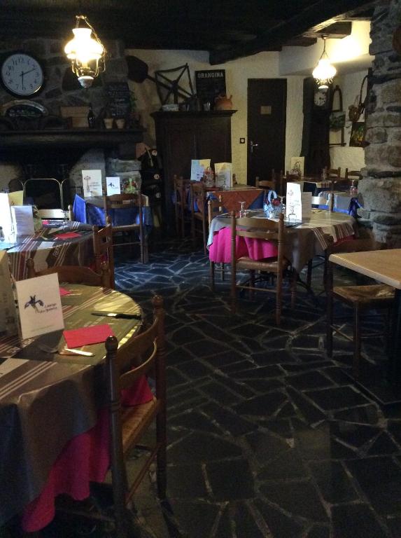 een eetkamer met tafels en stoelen en een klok bij Auberge des Pyrénées in Sainte-Marie-de-Campan