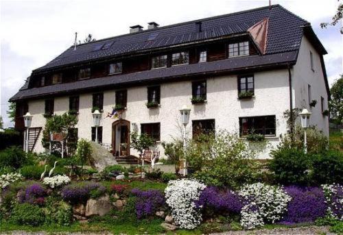 duży biały dom z kwiatami przed nim w obiekcie Hotel Das Landhaus w mieście Höchenschwand