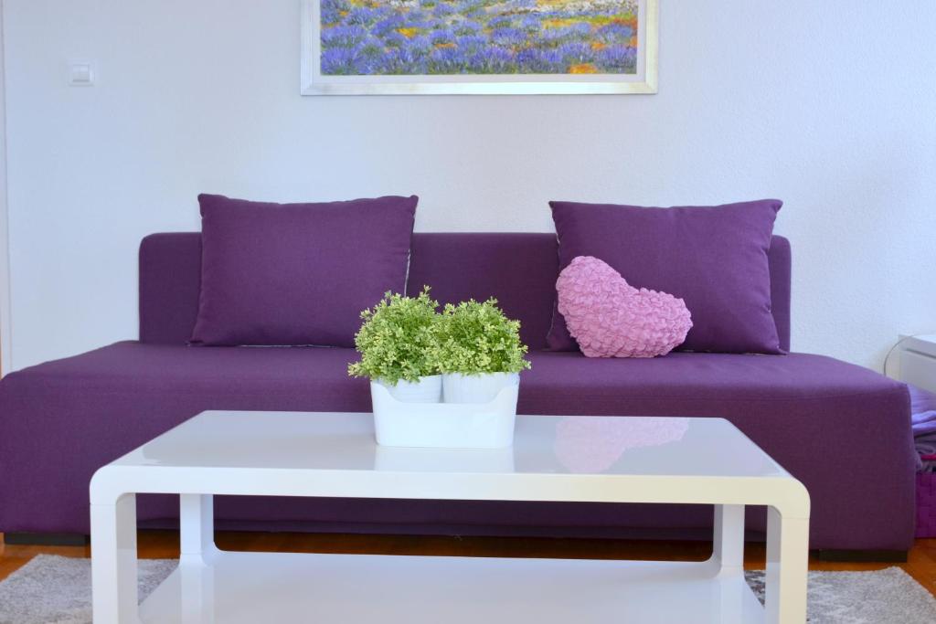a purple couch with a white coffee table with a potted plant at Iris beach apartments in Kaštela