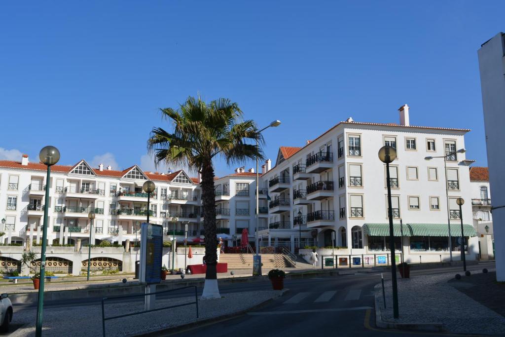 a city street with buildings and a palm tree at Ericeira Holidays- apartment T1 in Ericeira