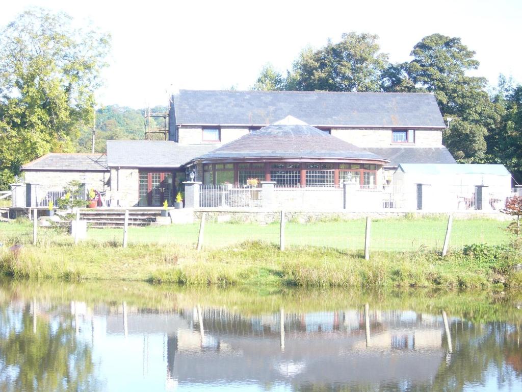 uma casa grande com um lago em frente em The Countryman Inn em Llantrisant