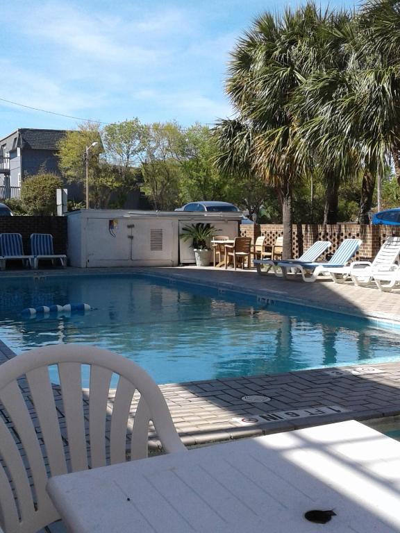 einen Pool mit Stühlen, einem Tisch und Bäumen in der Unterkunft David&#39;s Landing in Myrtle Beach